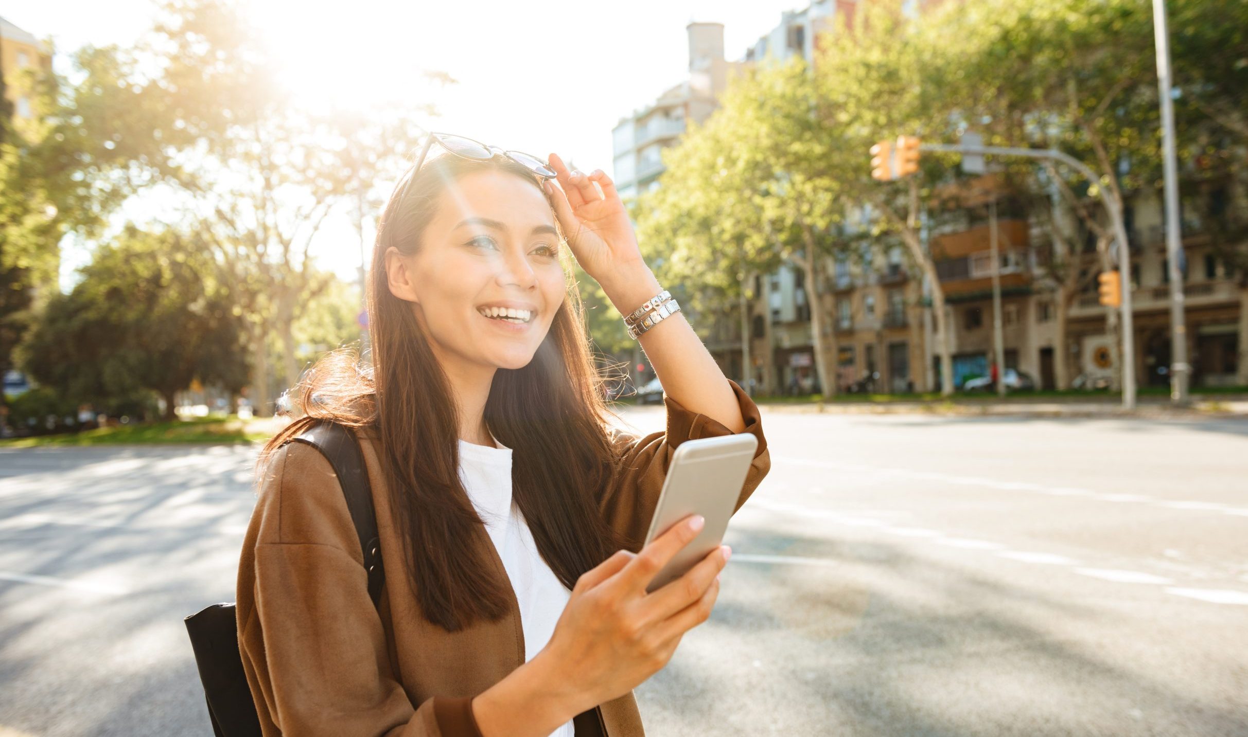 Image of amazing happy beautiful woman walking outdoors using mobile phone.