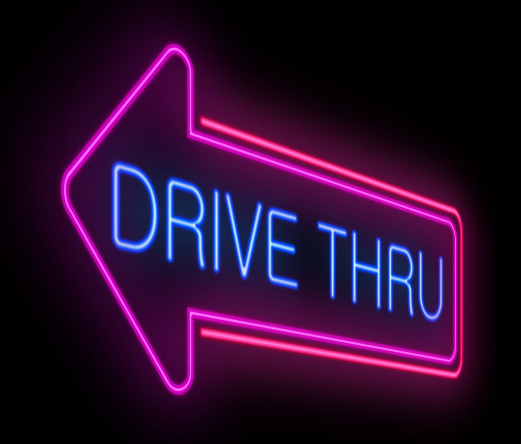Neon drive thru sign with pink arrow pointing left