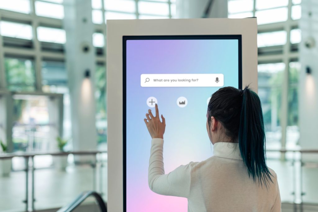 Woman interacting with digital directory touchscreen with her hand