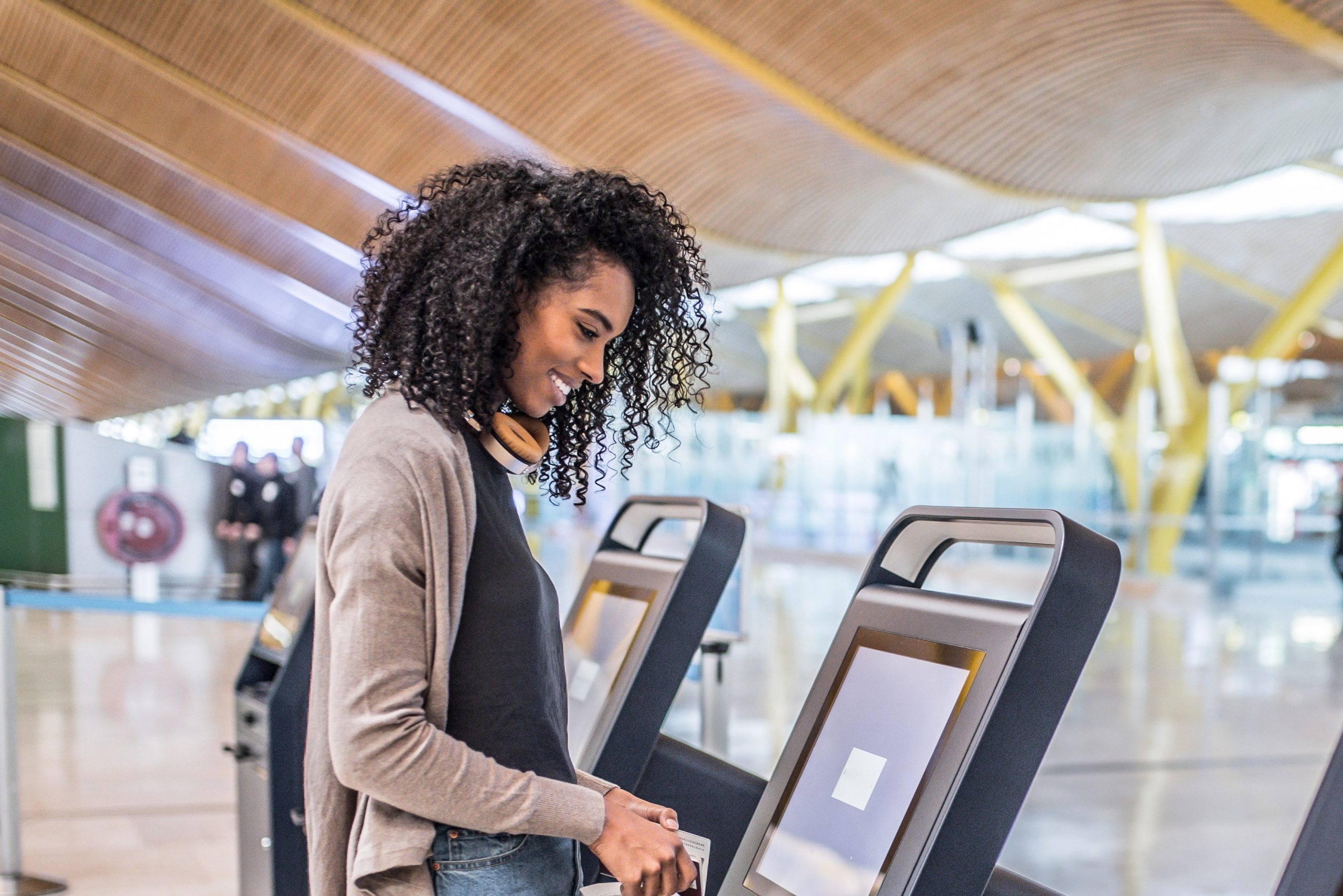 Woman of colour smiling down at check-in kiosk in service centre